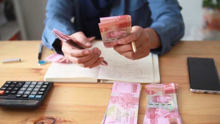 Seorang pria menghitung lembar seratus ribu rupiah