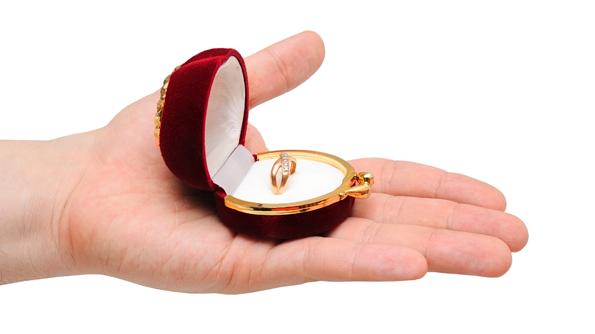 Seseorang sedang memegang kotak cincin emas